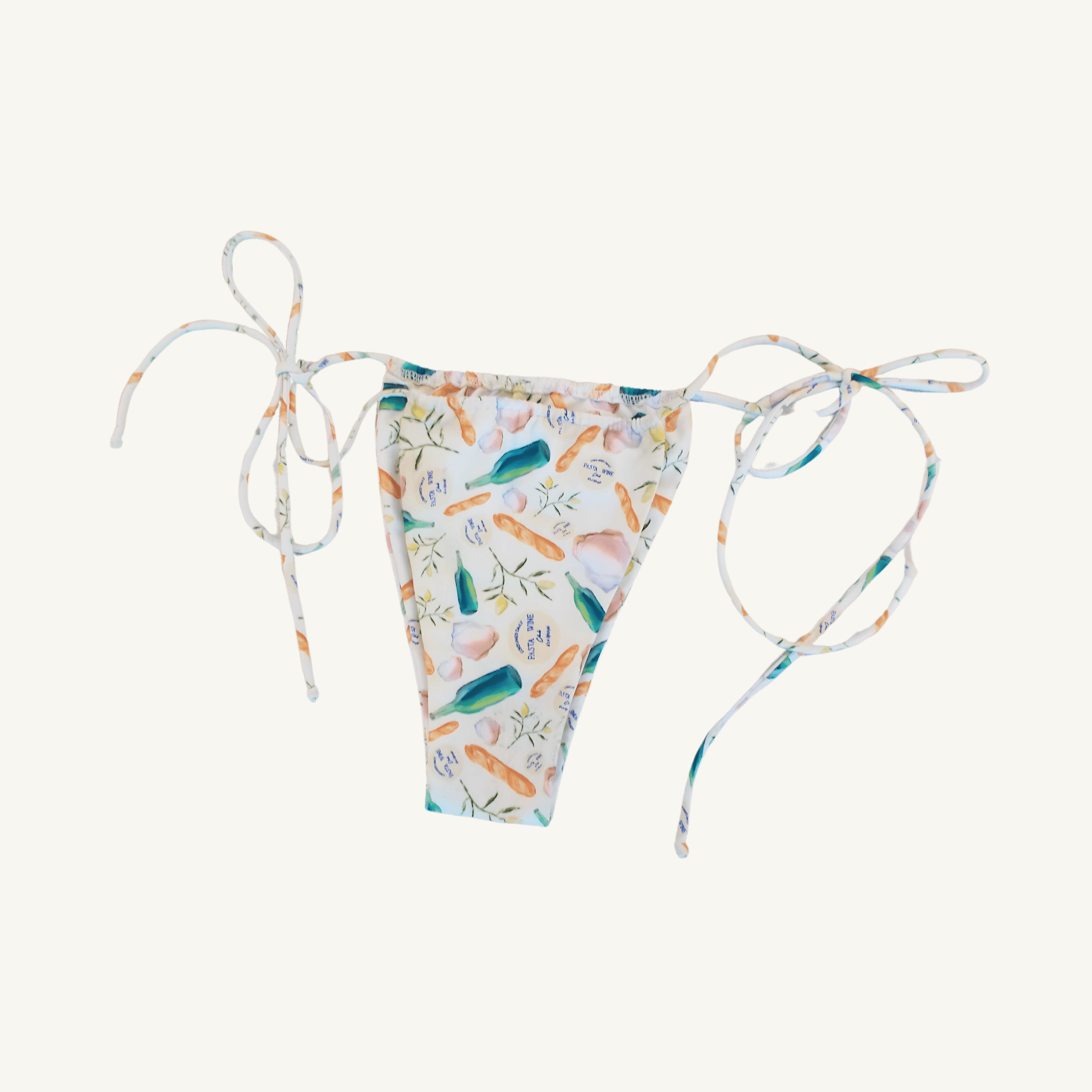 Close-up image of a women's bikini bottom featuring adjustable side ties and a colorful print with bottles, bread, leaves, and text in pastel tones on a white background, highlighting its stylish and playful beachwear design. | PicSEO 1778548920291