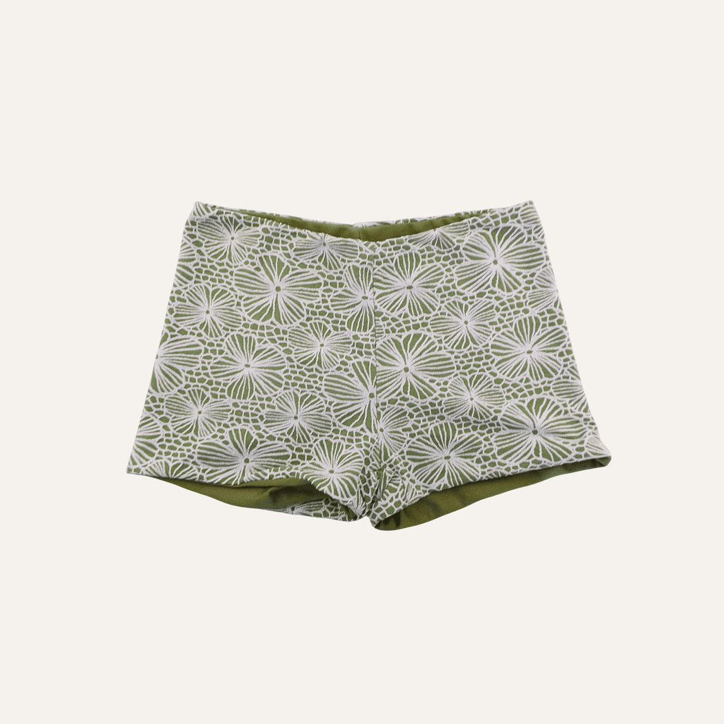 Olive green shorts featuring an intricate white floral lace overlay design, combining casual comfort with elegant detailing for a stylish summer look. | PicSEO 1776735084788