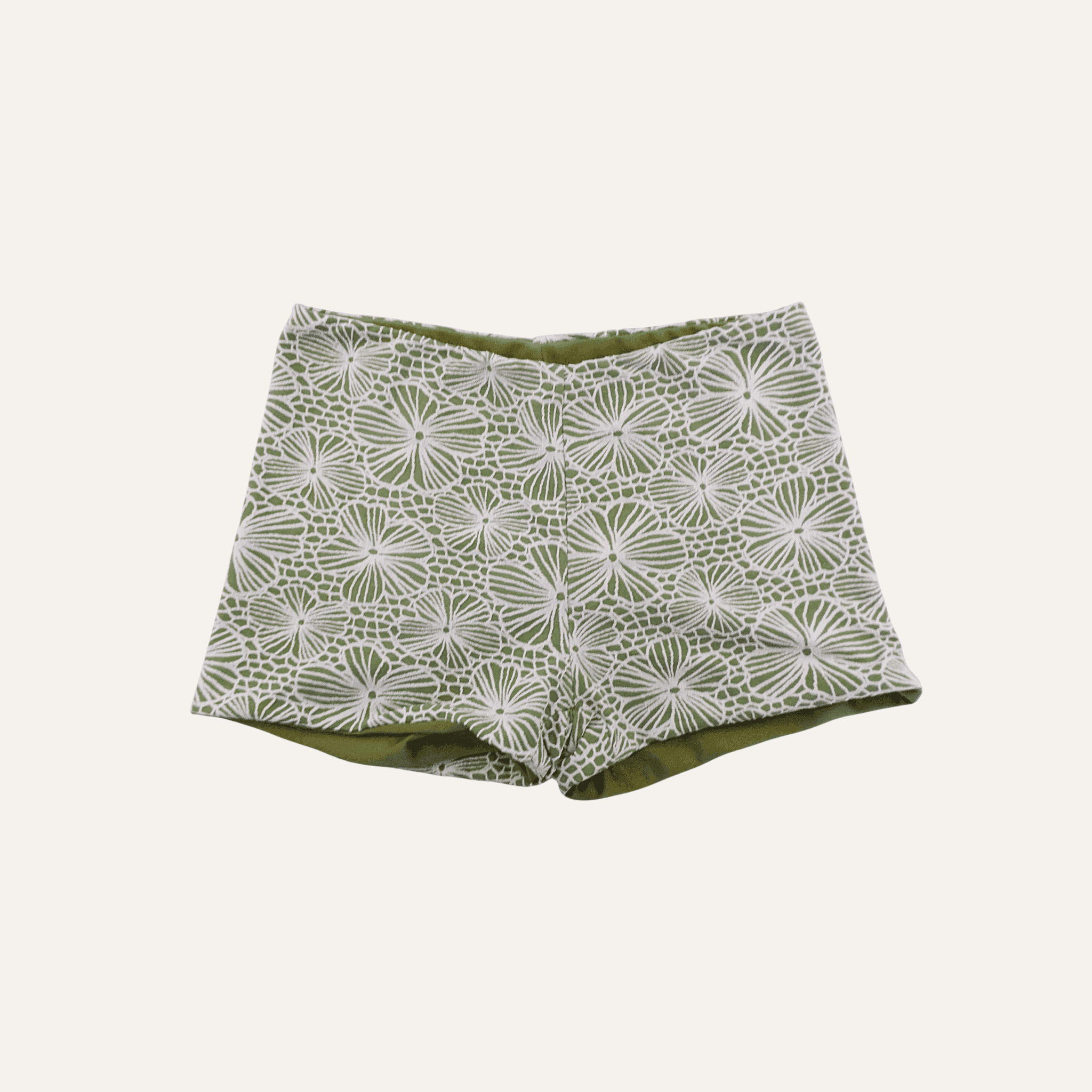 Olive green shorts featuring a white floral and geometric lace pattern, designed with a fitted waistband and a clean, tailored silhouette for a stylish and elegant look. | PicSEO 1778308081015